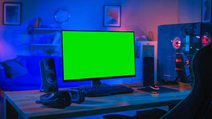 Powerful Personal Computer Gamer Rig with Mock Up Green Screen Monitor Stands on the Table at Home. Cozy Room with Modern Design is Lit with Blue and Neon Light.