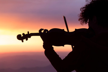 Silhouette of a woman with a violin at sunset.