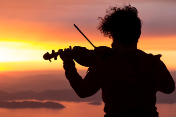 Silhouette of a woman with a violin at sunset.