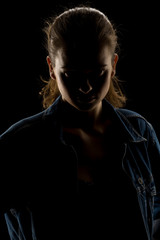 Silhouette of young unknown woman on black background