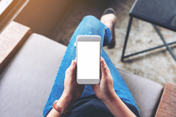 Top view mockup image of woman holding white mobile phone with blank screen while sitting in cafe