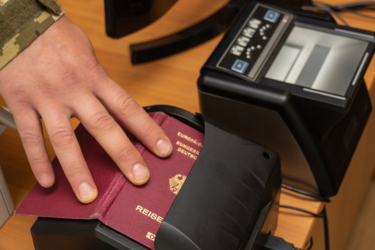 The process of scanning a German biometric passport to register the fact of crossing the state border. Male hand applies a passport to the scanning device. Concept of overseas travel