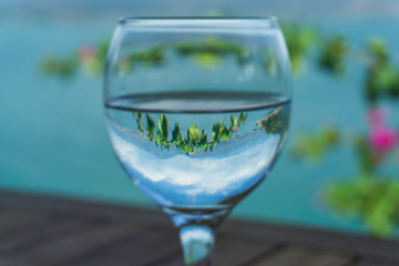 Glass of water with closeup on ocean and mountain nature blur background