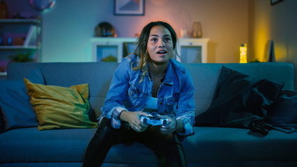 Beautiful Excited Young Black Gamer Girl Sitting on a Couch and Playing Video Games on a Console....