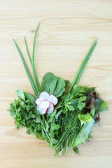 Spring mix. Fresh green salad. Green salad bouquet with radish flower on wooden background with copy space