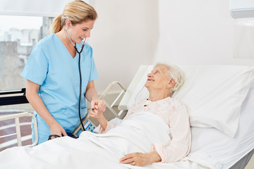 Fototapeta premium Nurse with stethoscope at the bedside