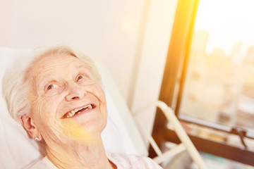 Happy elderly woman in bed in nursing home