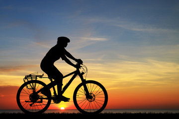 Silhouette man  and bike relaxing on blurry sunrise  sky   background.