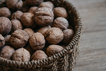 Walnuts in a round wicker basket on a wooden background. Close up.