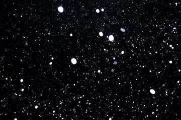 Obraz premium falling snow on a black background, snowfall at night, white chaotic spots on a black background