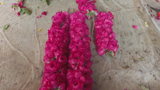 Slow motion 4k close-up of different flowers of India at a fresh morning market in Delhi with various popular floral items and various small vendors selling their produce, selling packaging garland 