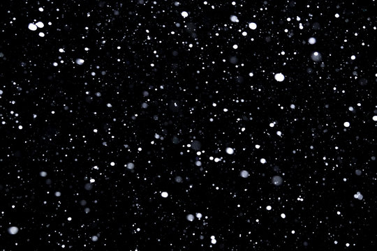 falling snow on a black background, snowfall at night, white chaotic spots on a black background