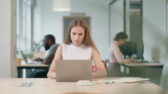 Business woman working at laptop at coworking. Portrait of concentrated lady.