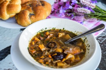 Plate with mushroom soup, bread and flowers.