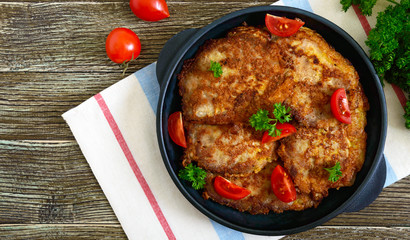 Tasty pork chop, serve on a cast-iron pan on a wooden table. Schnitzels. Top view, flat lay.