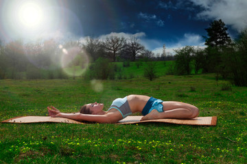Frau macht Yoga auf Wiese im Freien