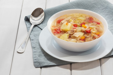 Fresh cabbage soup in white bowl on white wooden background with grey linen napkin. Traditional Russian shchi