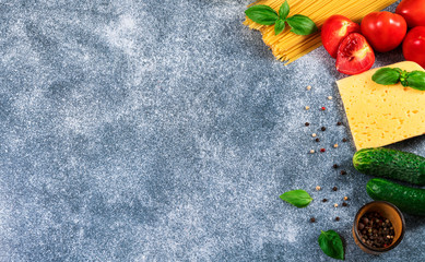 Pasta, tomatoes, cheese, basil and  oil on gray background