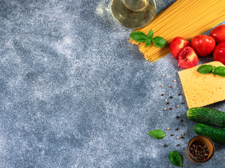 Pasta, tomatoes, cheese, basil and  oil on gray background