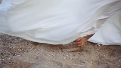 barefoot woman in gorgeous long loose white skirt walks on sandy beach close low angle shot slow motion