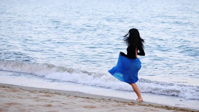 happy girl dancer in chiffon skirt runs gracefully with ballet pose in sea edge water on empty beach in dusk slow motion