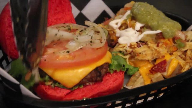 Laying onions on a hamburger  along side with fries bathed with cheese, meat and other ingredients.