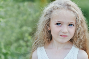 Fototapeta premium Close up portrait of beautiful little girl with blonde long hair and big blue eyes