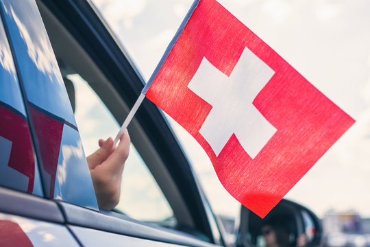 Woman or Girl Holding Swiss Flag from the open car window. Concept