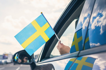 Woman or Girl Holding Swedish Flag from the open car window. Concept