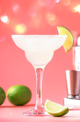 Lime margarita alcoholic cocktail with silver tequila, liqueur, lime juice, sugar syrup, salt and ice, festive trendy pink background, copy space