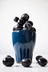A bunch of big black grapes in a blue cup