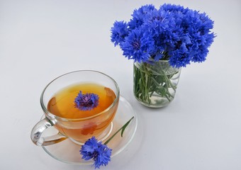 Herbal tea with a blue cornflower in a glass cup on a white background, herbal medicine.