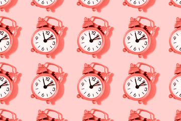 Muster mit Wecker auf korallenrotem Hintergrund. © Yulia Lisitsa