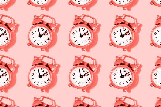 Pattern made with alarm clock on coral background.