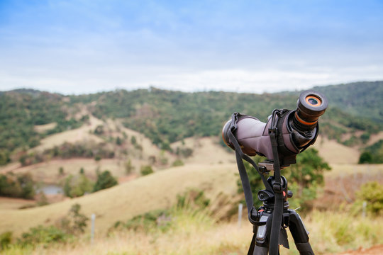 spotting scope or monocular on blurred green mountain as background
