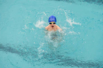 top view of a 7-year boy playing and swimming in the swimming pool