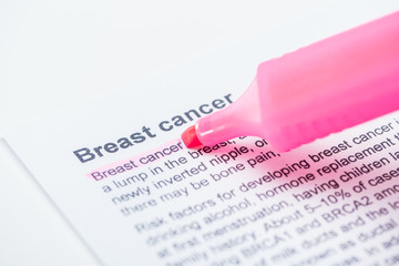 close up view of print newspaper with breast cancer article and pink marker on white background