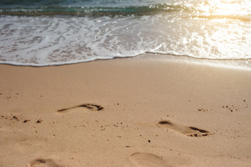 Footprints of human feet on the sand near the water on the beach