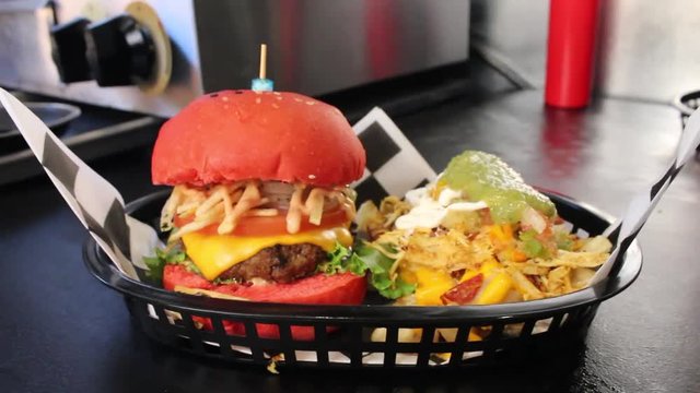 Preparing a DELICIOUS looking HAMBURGER  along side with some FRIES bathed with CHEESE an other INGREDIENTS