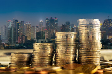 double exposure of golden Coin stacks on table with blur city night background, business investment concept 