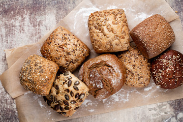 Gold rustic crusty loaves of bread and buns on wooden background. Still life captured from above top view, flat lay.