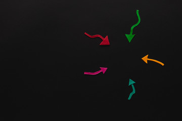 A group of arrows made from plasticine all pointing towards one another on black background, shot...