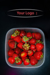 Fresh strawberries in plastic container, with copy space. Vertical