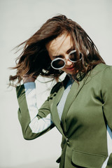 Outdoor full fashion portrait of fashionable cute woman wearing sunglasses. Model posing in street of european city