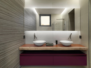Fototapeta na wymiar interior shot of a modern bathroom in the foreground the sink cabinets with two counter top wash basin on them