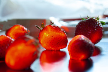 Ripe strawberries with leaves in wicker basket on table on blurred background