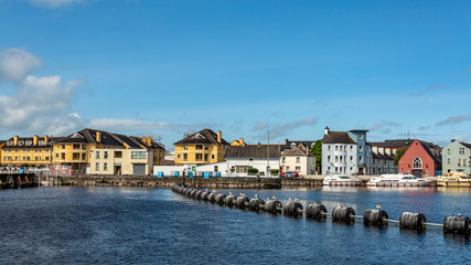River Shannon with plastic buoys on the calm water of the river, cityscape with quaint houses in...