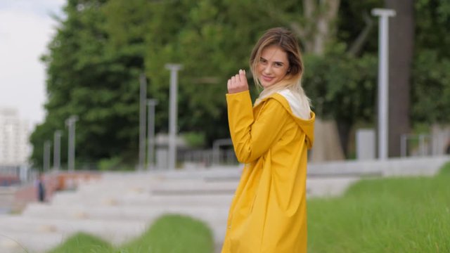 Pretty young girl in yellow rain coat smoking cigarette enjoy walking alone in good mood