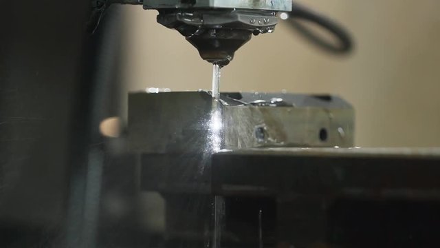 Close up EDM manufacturing process shapes metal by creating sparks