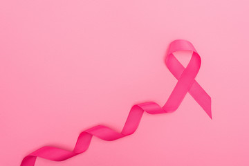 top view of curved crimson breast cancer sign on pink background